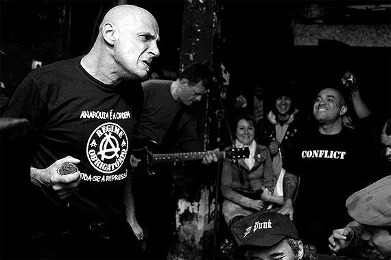 Vocalista da banda punk Vento Sul cantando no meio do público, em foto preto e branco